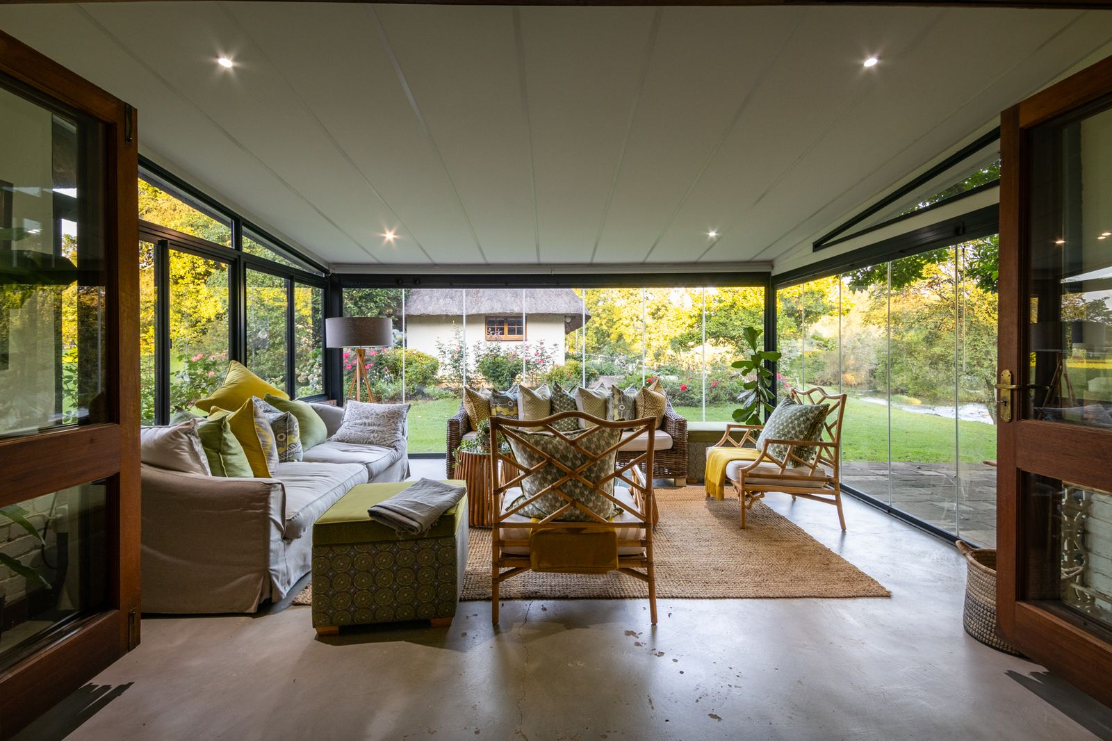 A furnished garden room with doors open onto a lawn