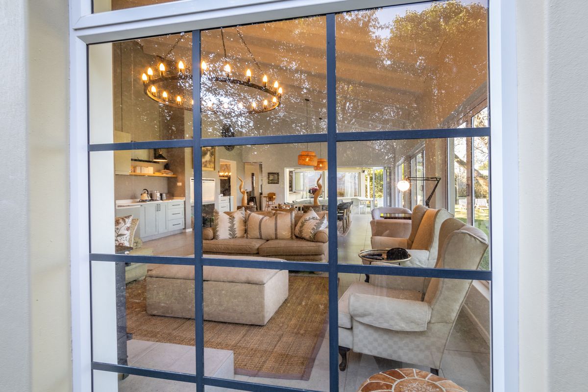 A warmly lit lounge seen through a paned window, with a candle chandelier